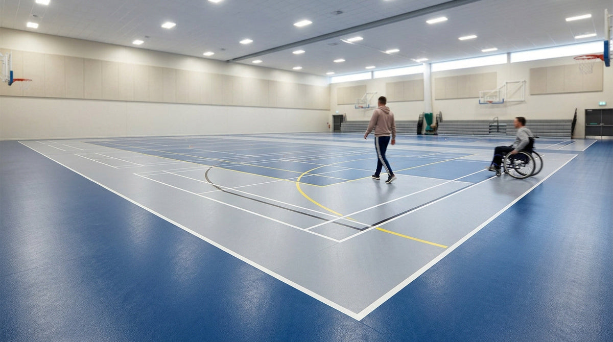 Gymnase intérieur avec sol sportif bleu et gris, tracés multisports et paniers de basketball