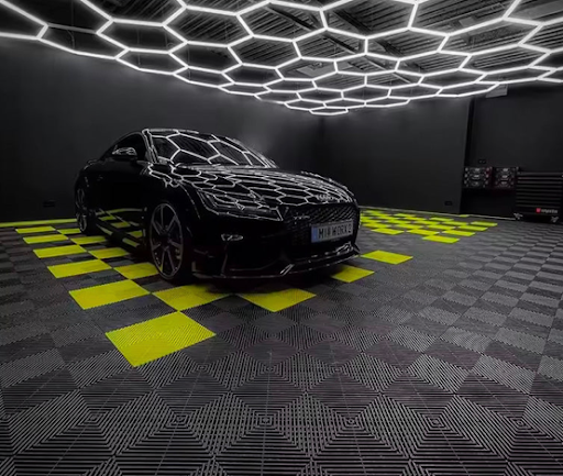 Voiture noire brillante stationnée dans un showroom ou un atelier automobile équipé d'un sol de garage