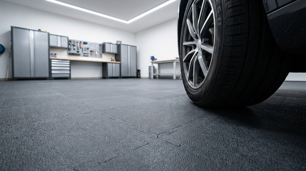 Roue de voiture avec jante en alliage au premier plan sur le sol d’un garage ou d’un atelier automobile