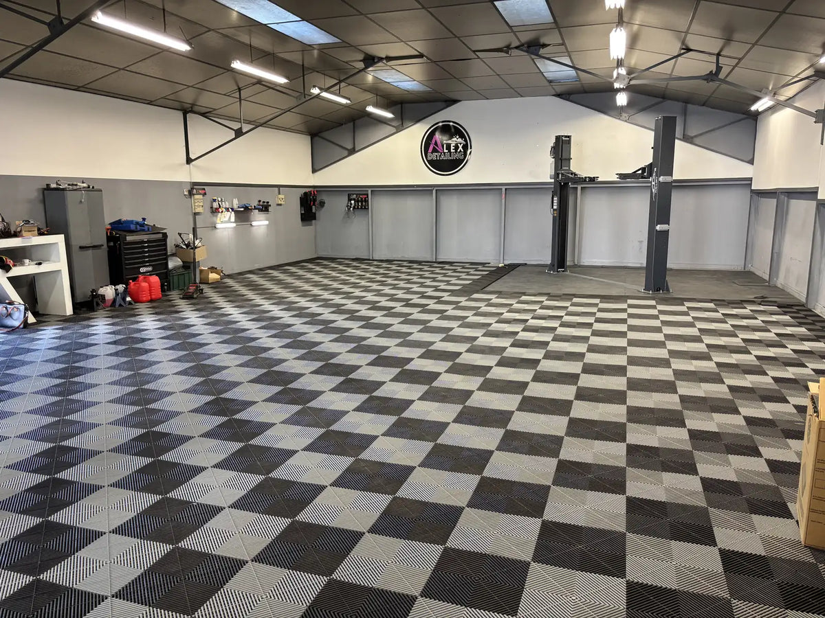 Atelier Alex Detailing après pose : 400 m² de dalles ajourées AERO noir et gris en damier, pont élévateur sur dalles ULTIMA noir