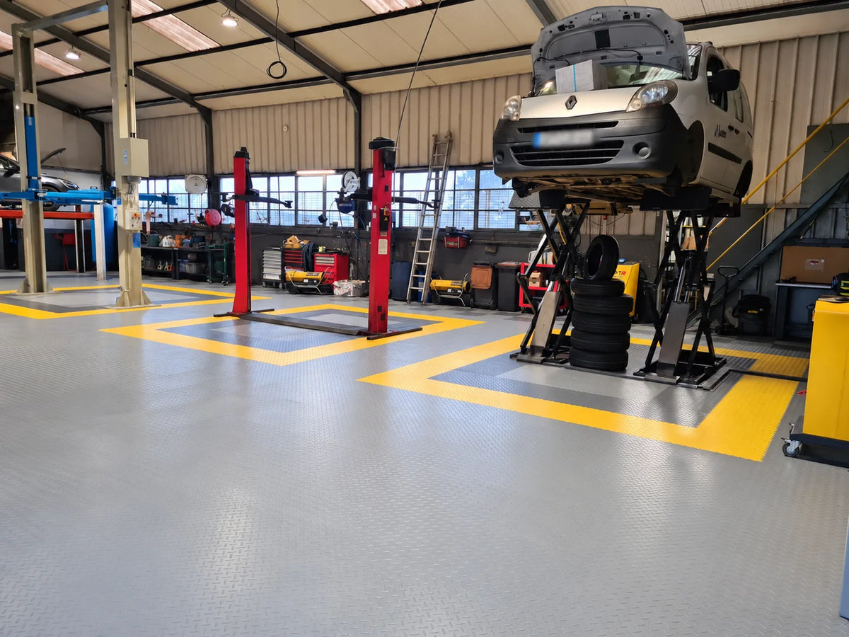 Pont ciseaux et ponts à colonnes posés sur les dalles PVC ULTIMA INDUSTRY, véhicule levé dans l'atelier Auto Diffusion 44