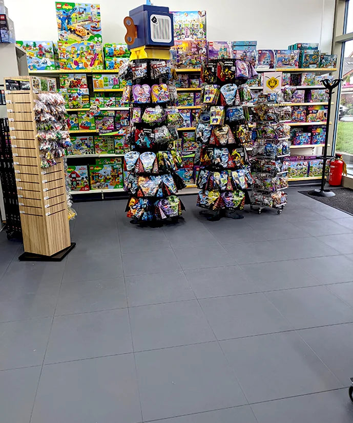Entrée du magasin BEETOYS : présentoirs tournants sur sol en dalles ULTIMA JOINTS INVISIBLES PURE gris foncé