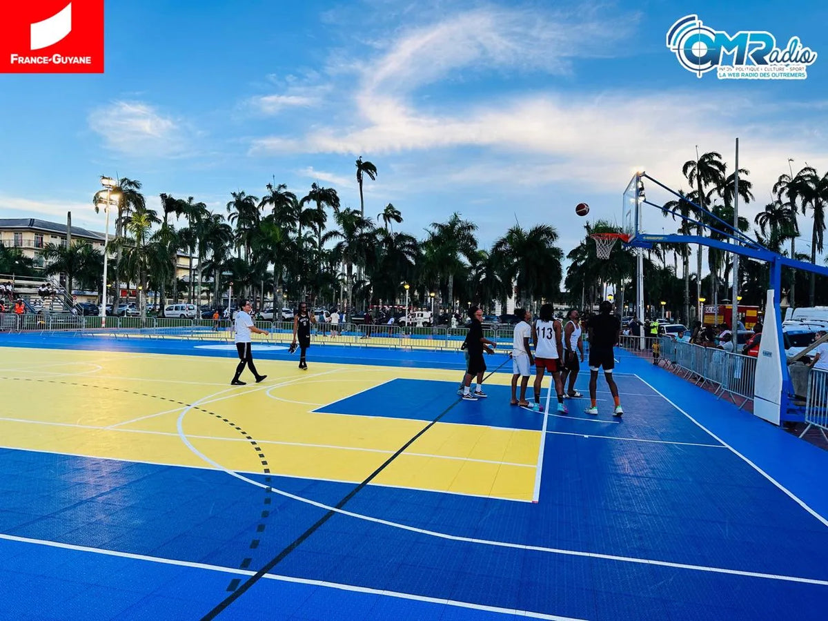 Terrain multisport extérieur de Cayenne en dalles BERGO ULTIMATE bleu et jaune, joueurs de basket sous les palmiers