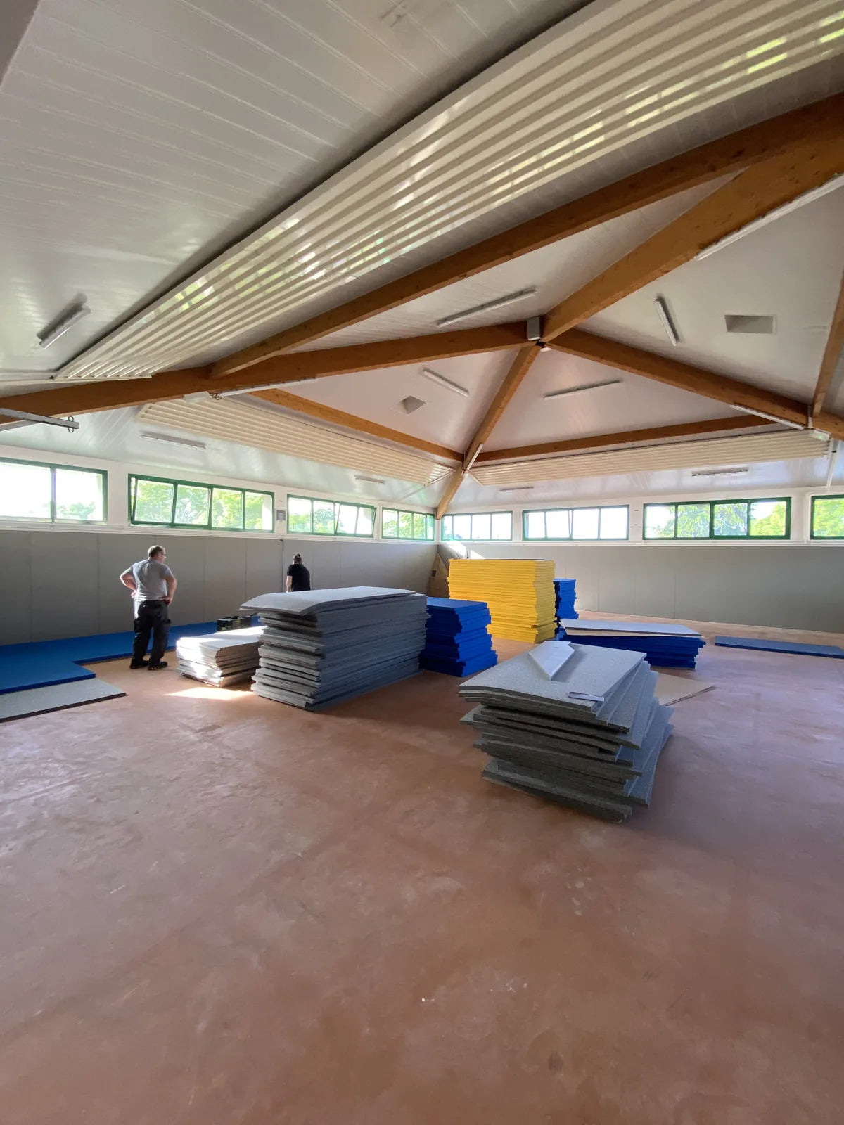Dojo de Saint-Genis-les-Ollières pendant la pose : plaques de sous-tapis mousse et tatamis bleus et jaunes empilés