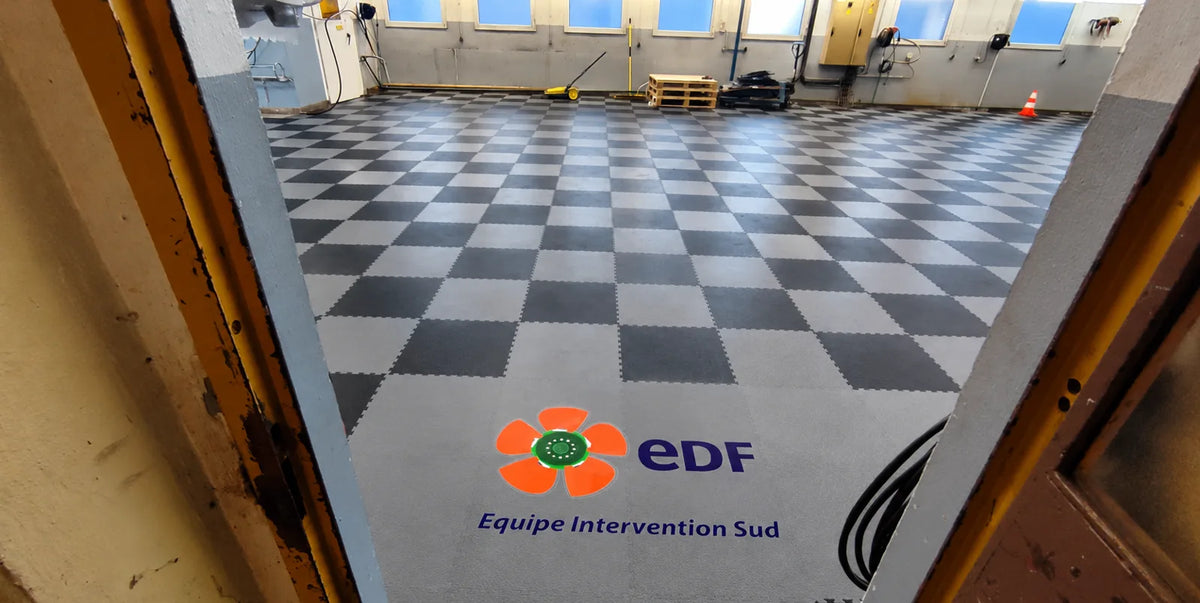 Atelier EDF Hydro Est : damier de dalles ULTIMA ULTRA noir et gris foncé avec logo EDF au sol