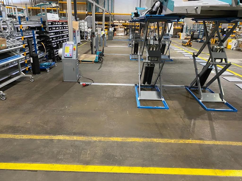 Usine EXOTEC avant travaux : béton brut autour des tables élévatrices de la ligne de montage
