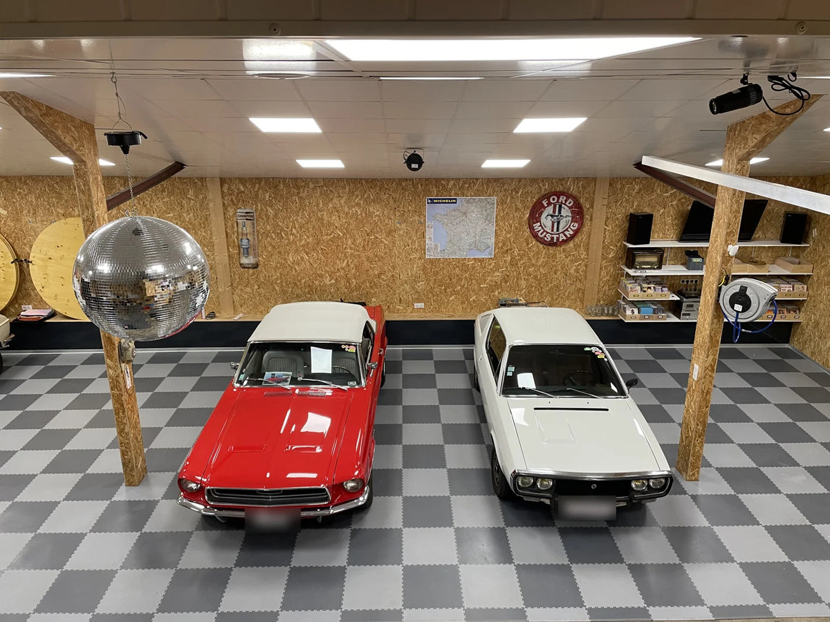 Garage privé en Belgique, sol en damier de dalles ULTIMA INDUSTRY gris foncé et gris clair sous deux voitures anciennes