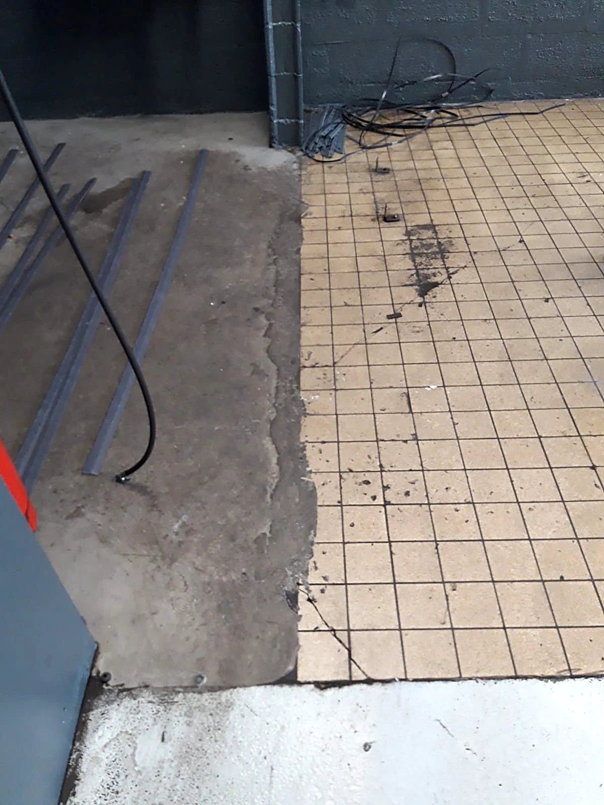 Avant : carrelage et béton à nu dans l'atelier d'un garage professionnel