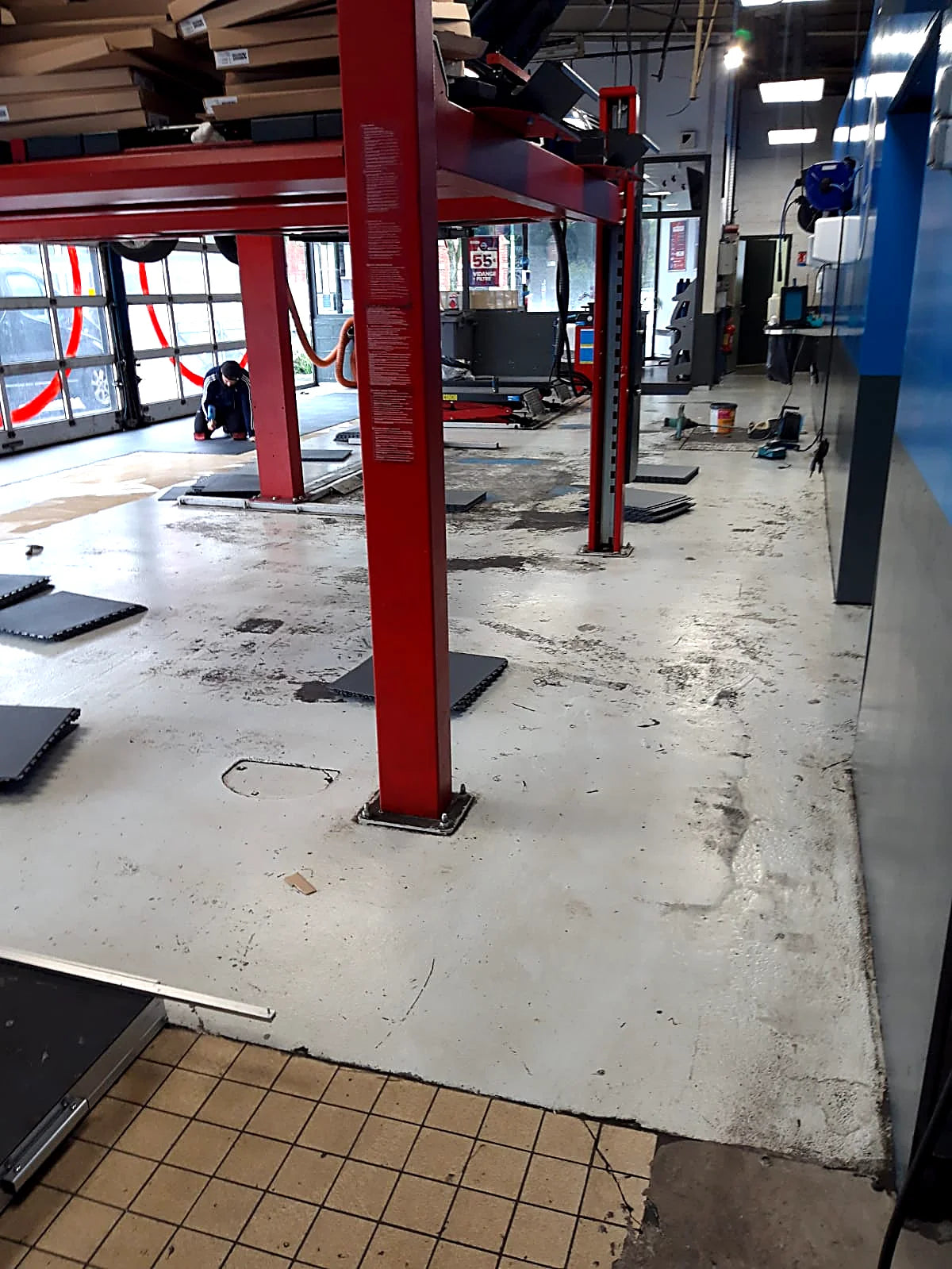 Avant : sol de garage professionnel abîmé et taché entre les ponts élévateurs