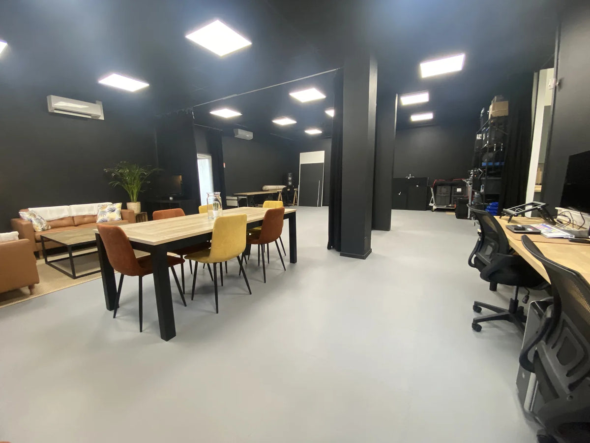 Studio audiovisuel Ici et Maintenant : coin salon, table de réunion et postes de montage sur dalles ULTIMA XL gris clair