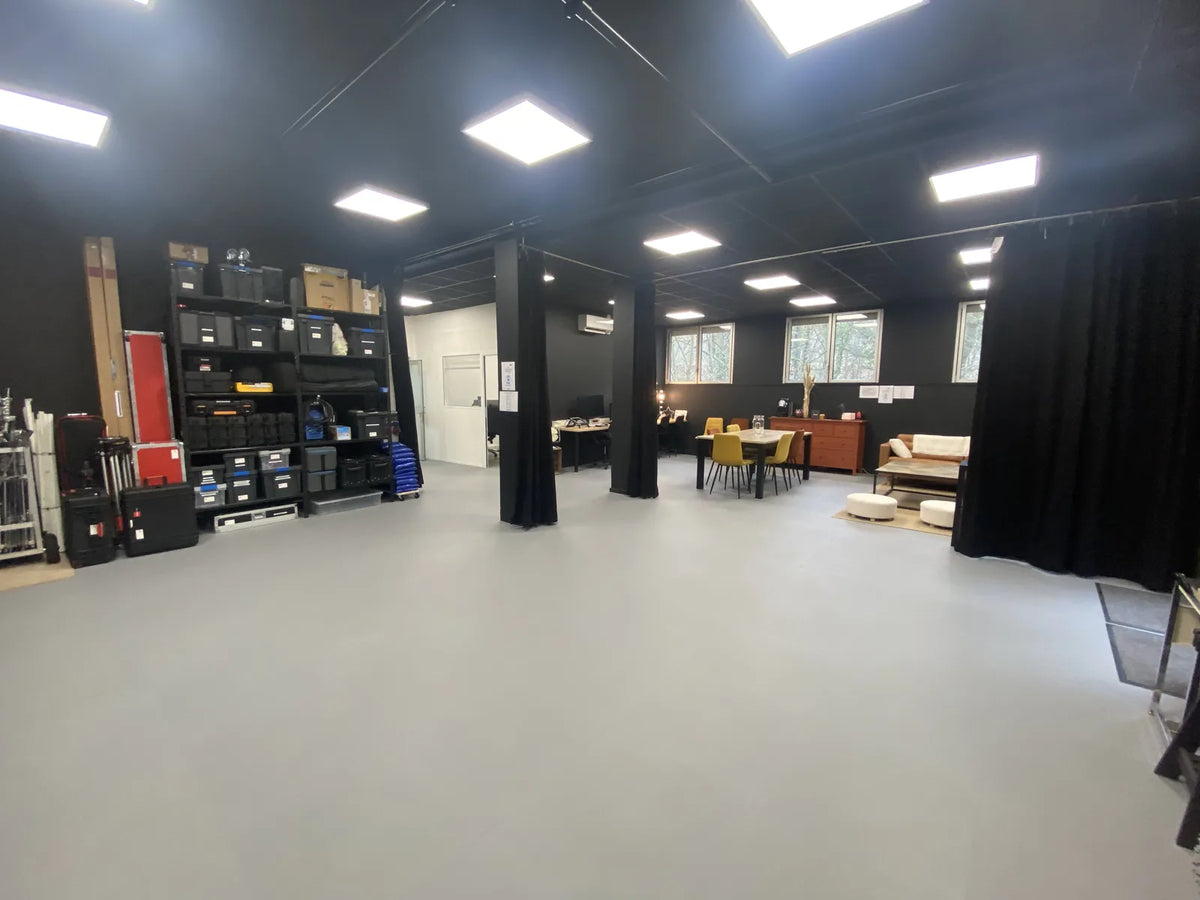 Plateau de tournage Ici et Maintenant : rideaux noirs, stock de matériel et sol en dalles PVC grand format ULTIMA XL gris clair