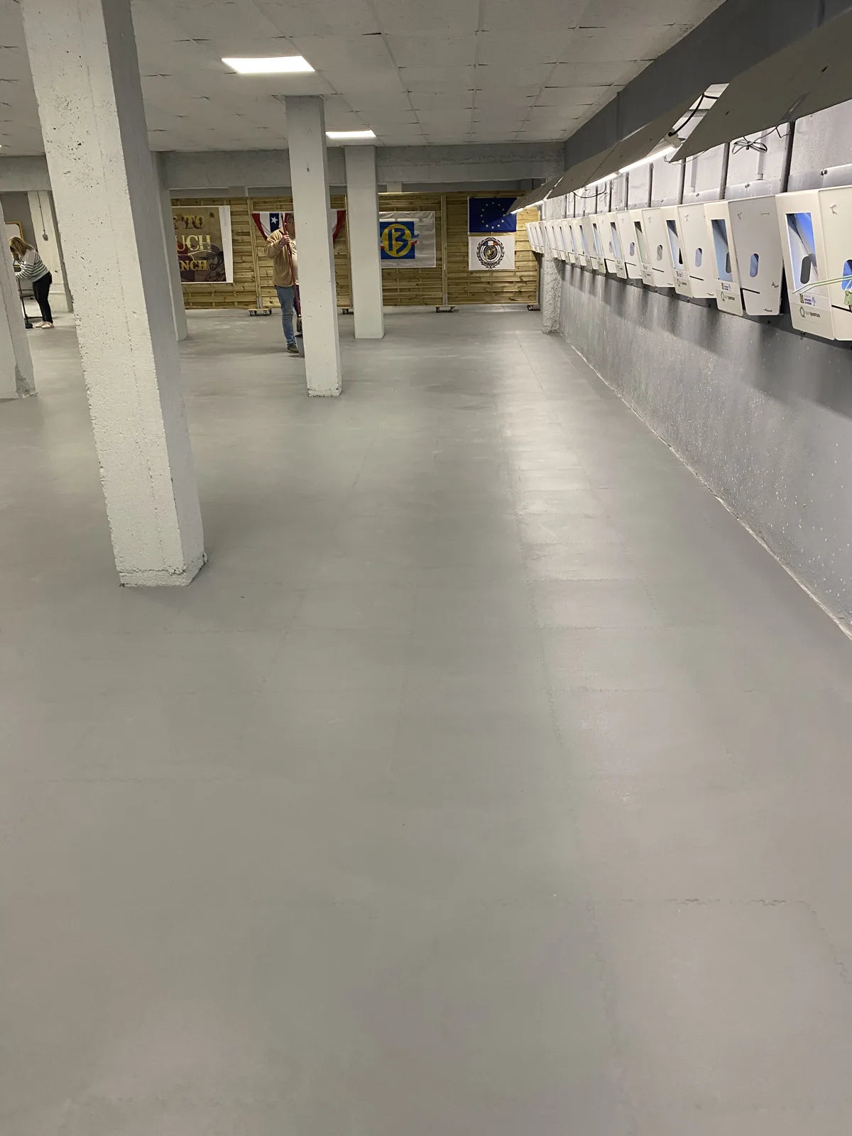 Vue du stand de tir d'Allauch après pose des dalles PVC gris clair, ligne de cibles au fond