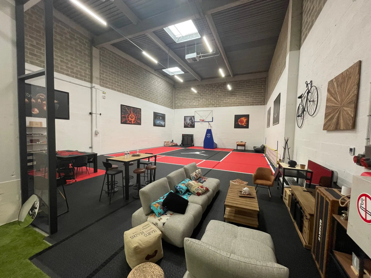 Espace d'entreprise avec salon et terrain de basket, sol continu en dalles BERGO ULTIMATE noires et rouges