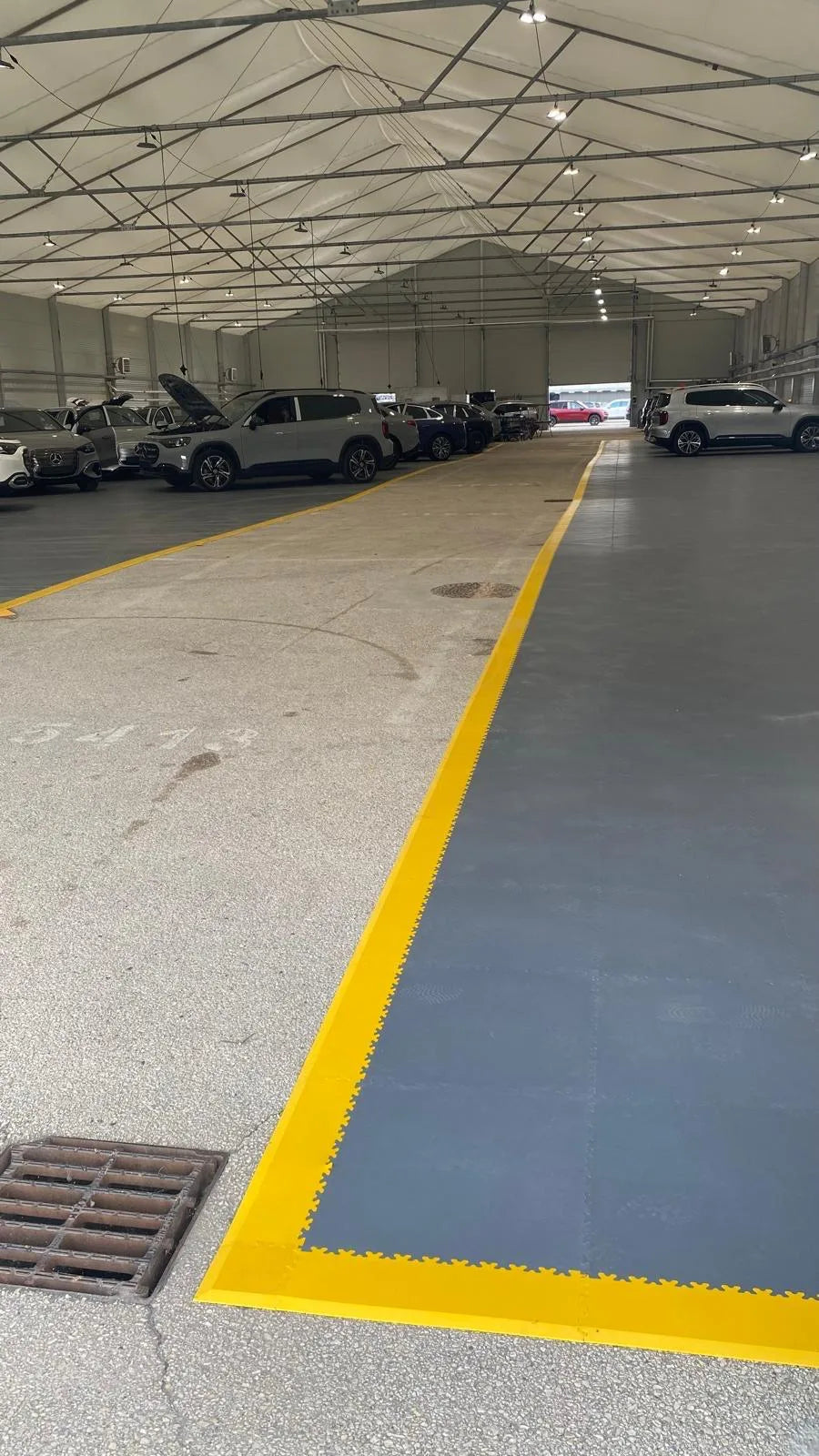 Bordure jaune d'une zone ESD en dalles PVC gris foncé, hall de véhicules Mercedes-Benz