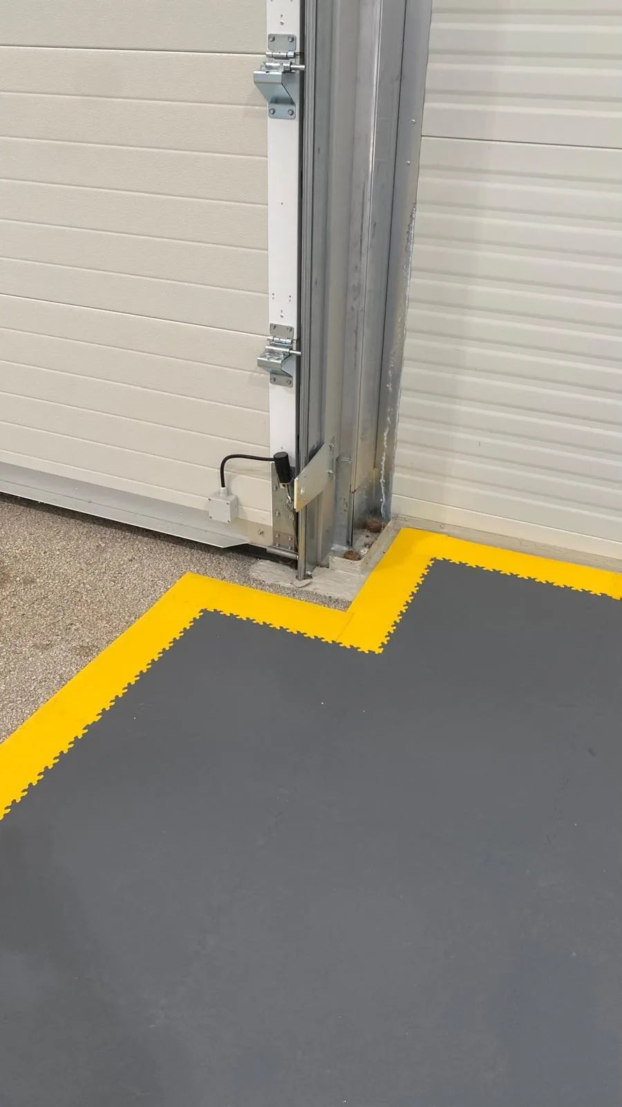 Finition de la bordure jaune des dalles ESD au pied d'une porte sectionnelle