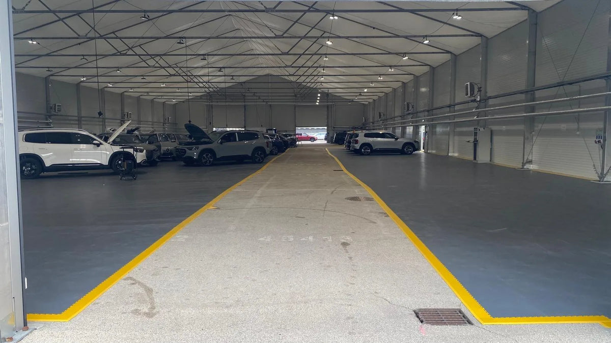 Hall Mercedes-Benz en Allemagne : dalles PVC ESD gris foncé de part et d'autre de l'allée, bordures jaunes