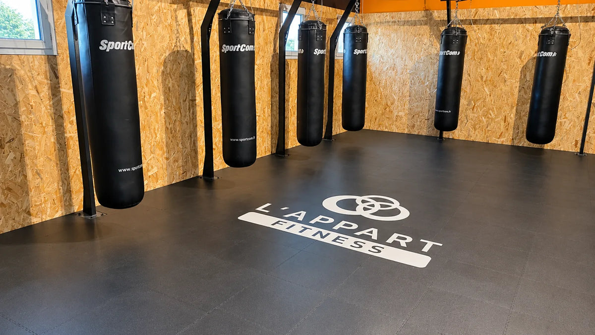 Espace boxe L'Appart Fitness après pose : dalles PVC ULTIMA INDUSTRY ECO PREMIUM noir avec logo imprimé au sol